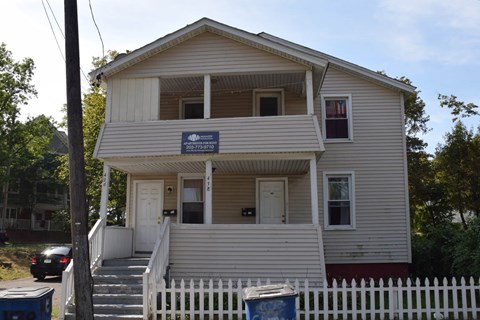 A two-story house with a white picket fence in front.
