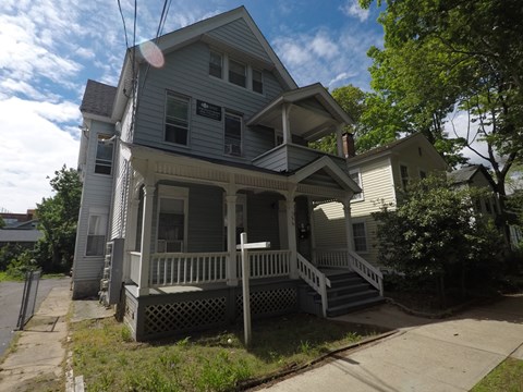 A two-story house with a porch and a front yard.