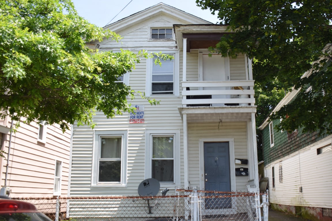 A two-story house with a blue door and a balcony.