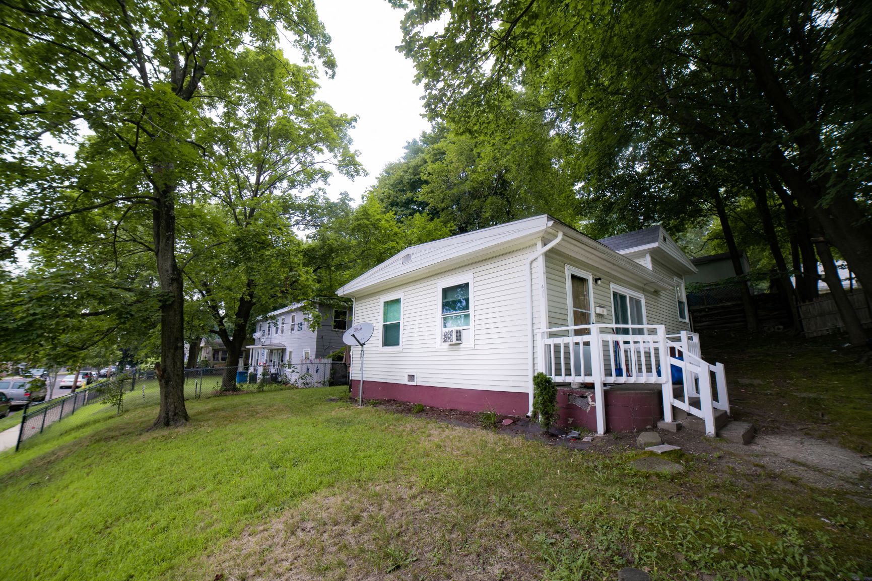 A small house with a porch is surrounded by trees.