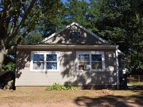 A small house with a grey siding and a brown roof.