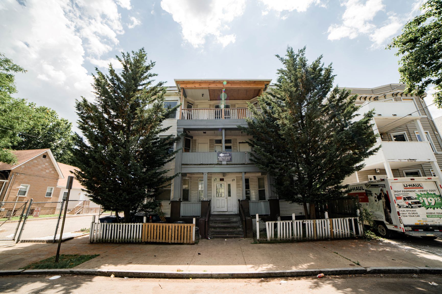 A two-story house with a front porch and a truck parked in front.