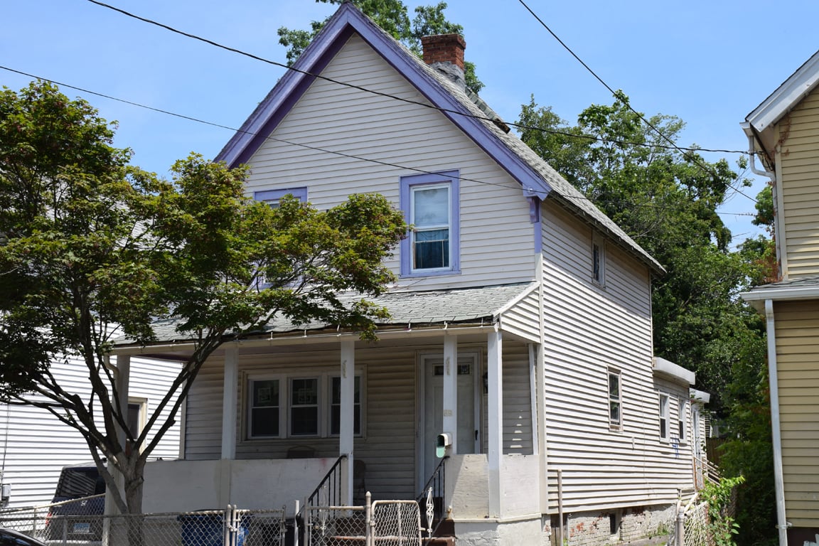 A house with a purple window and a tree in front.