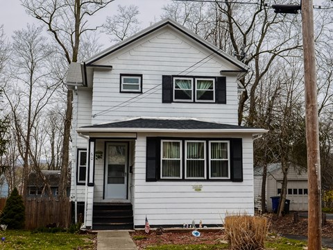 A white house with a grey door and a small porch.