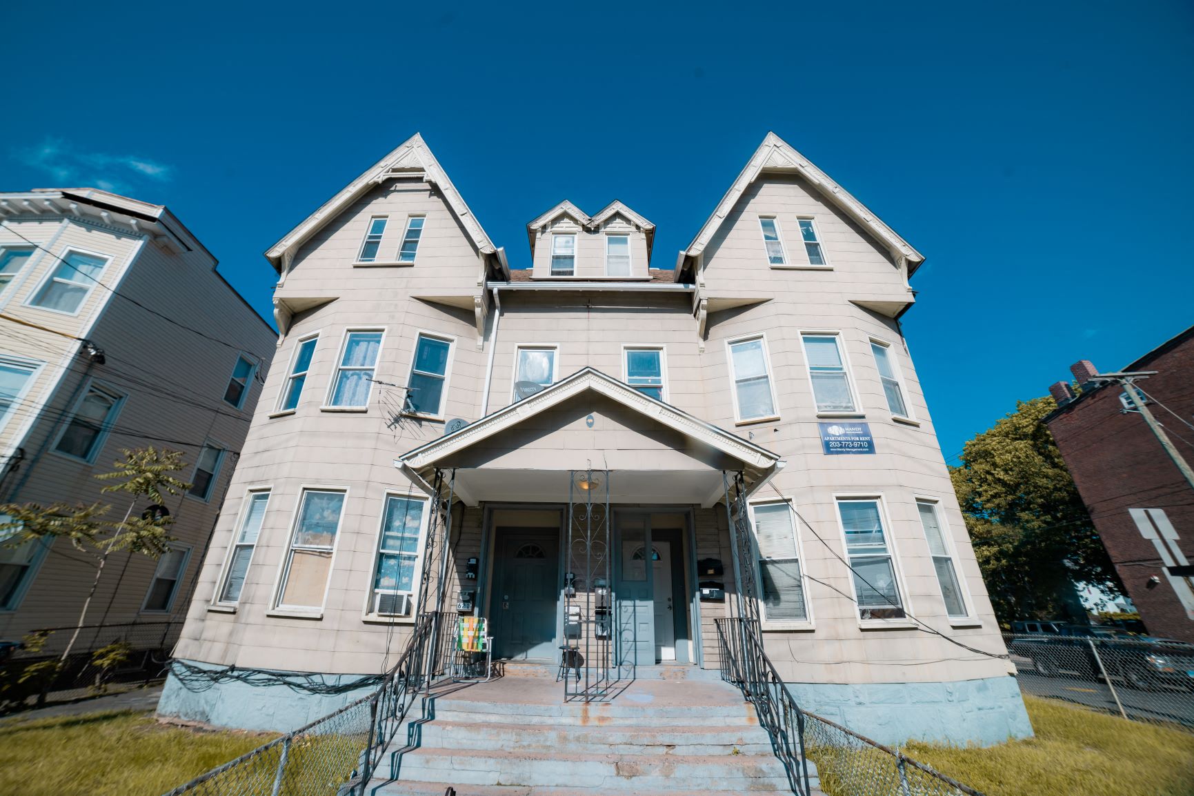 A large, two-story building with a front porch and a staircase leading to the entrance.