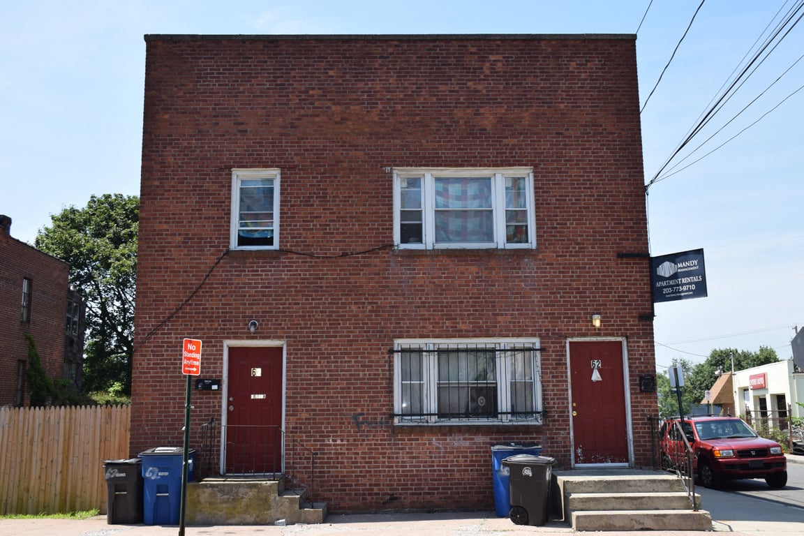 A red brick building with a sign that says "Apartments" on the top right corner.