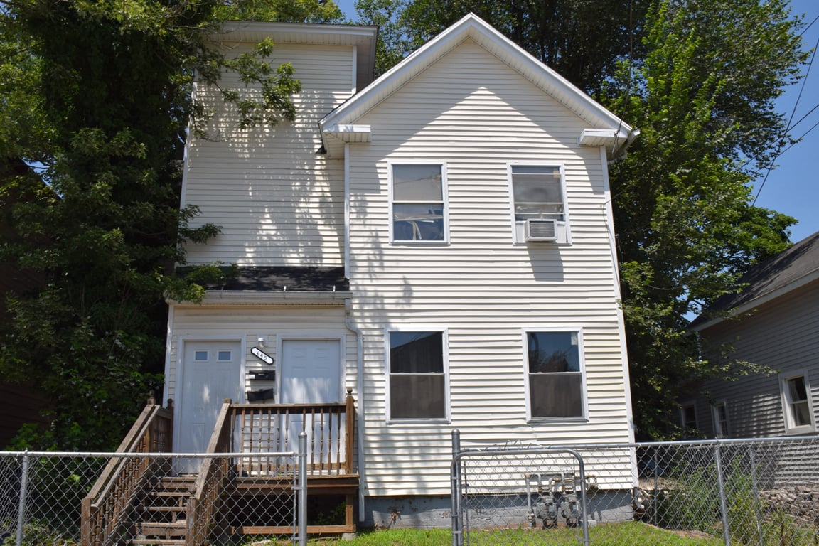 A white house with a porch and a fence.