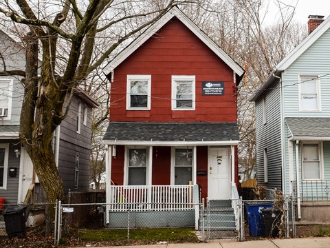 A red house with a white fence in front of it.