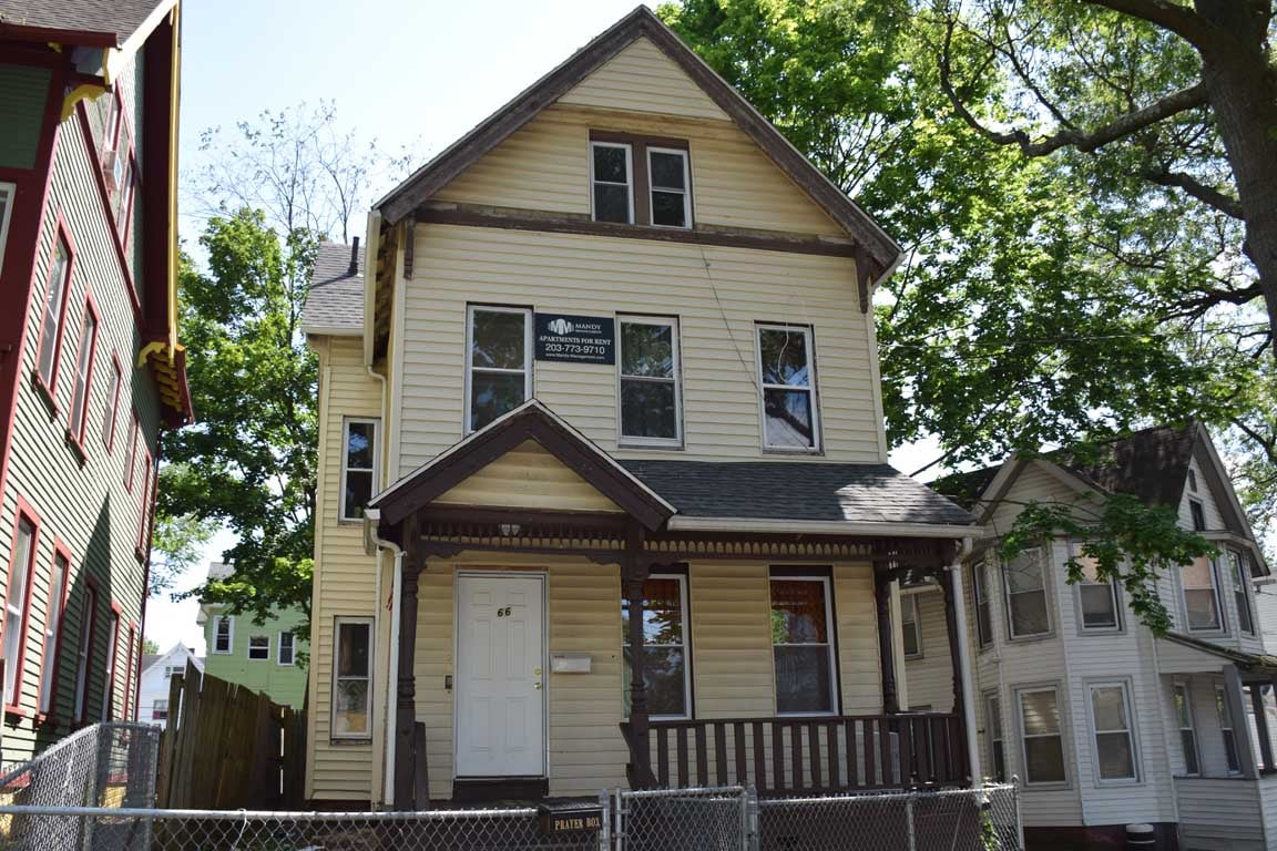 A yellow house with a white door and windows.