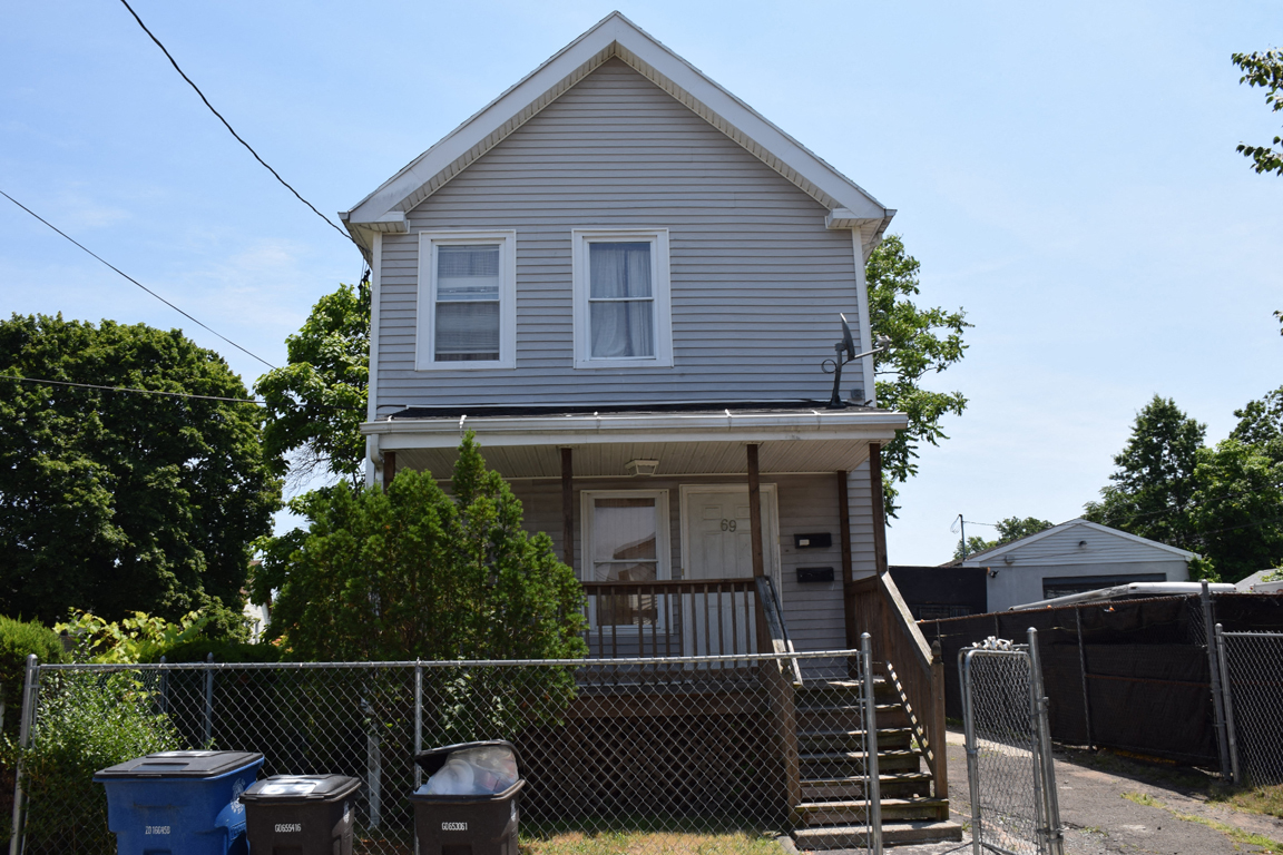 A two-story house with a grey siding and a white door.