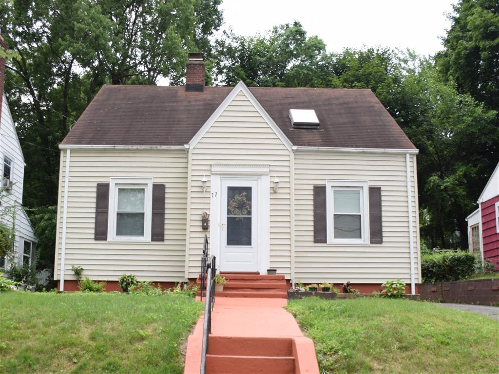 A small house with a red brick walkway leading to the front door.