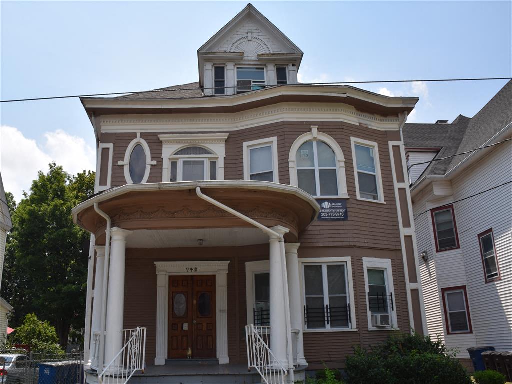 A brown building with a porch and a sign on it.