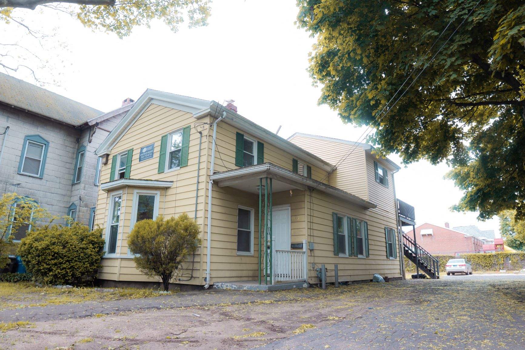 A yellow house with green shutters and a grey door.
