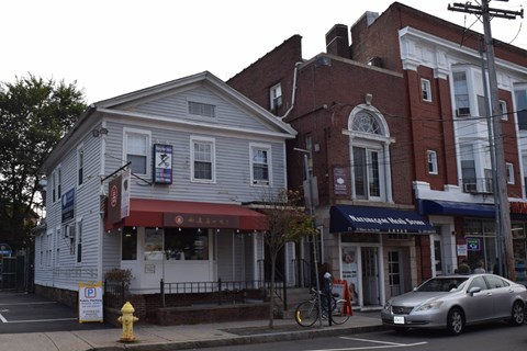 A white building with a red awning is next to a red brick building.