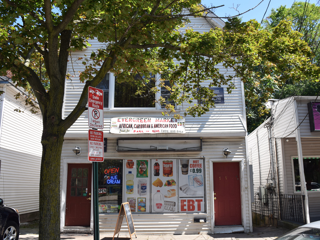 A storefront with a sign that says "Open 24 Hours" and "African Caribbean American Food".