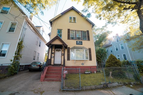 A yellow house with a red staircase in front.