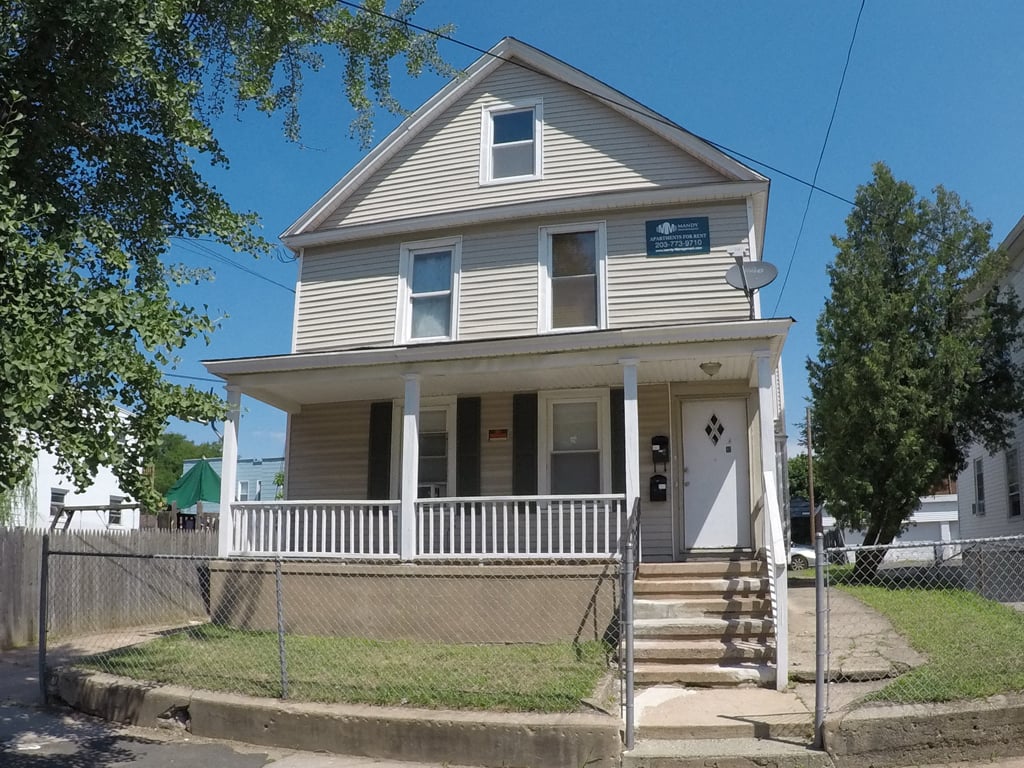 A two-story house with a porch and a fence.