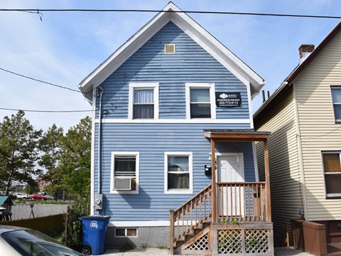 A blue house with a white door and windows.