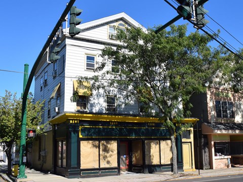 A white building with a yellow awning sits on a street corner.