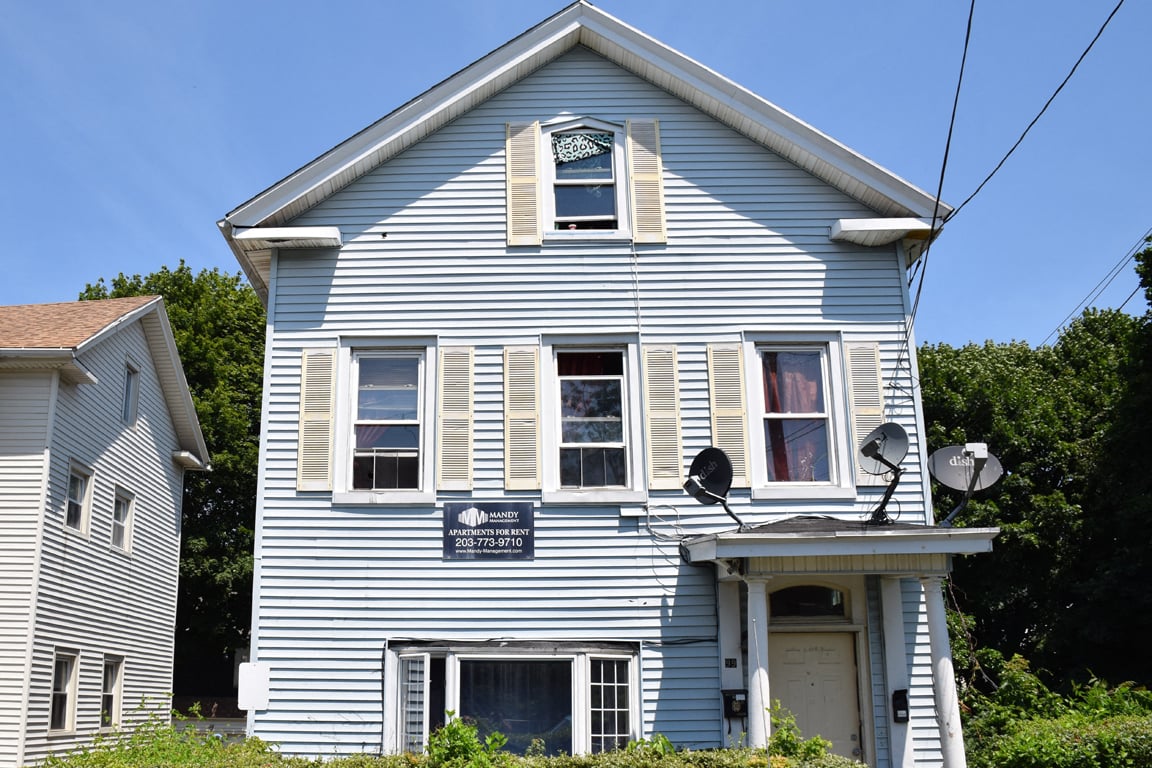A blue house with a sign that says "Welcome to the neighborhood" on the front.