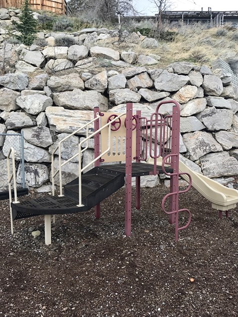 A playground with a slide and a climbing frame.