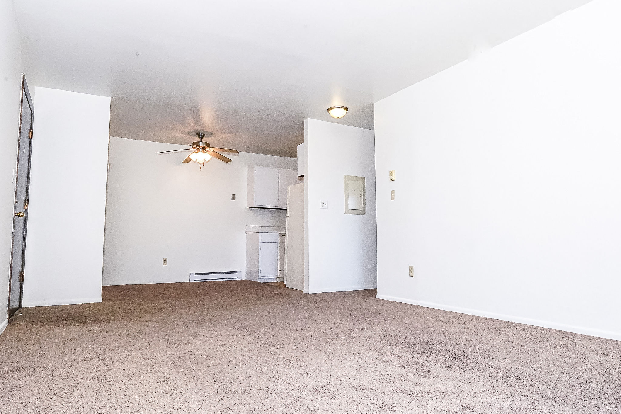 an empty living room with white walls and a ceiling fan
