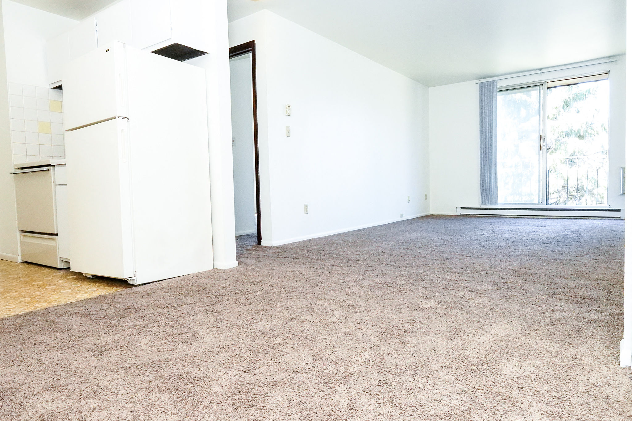 an empty room with a refrigerator and a window