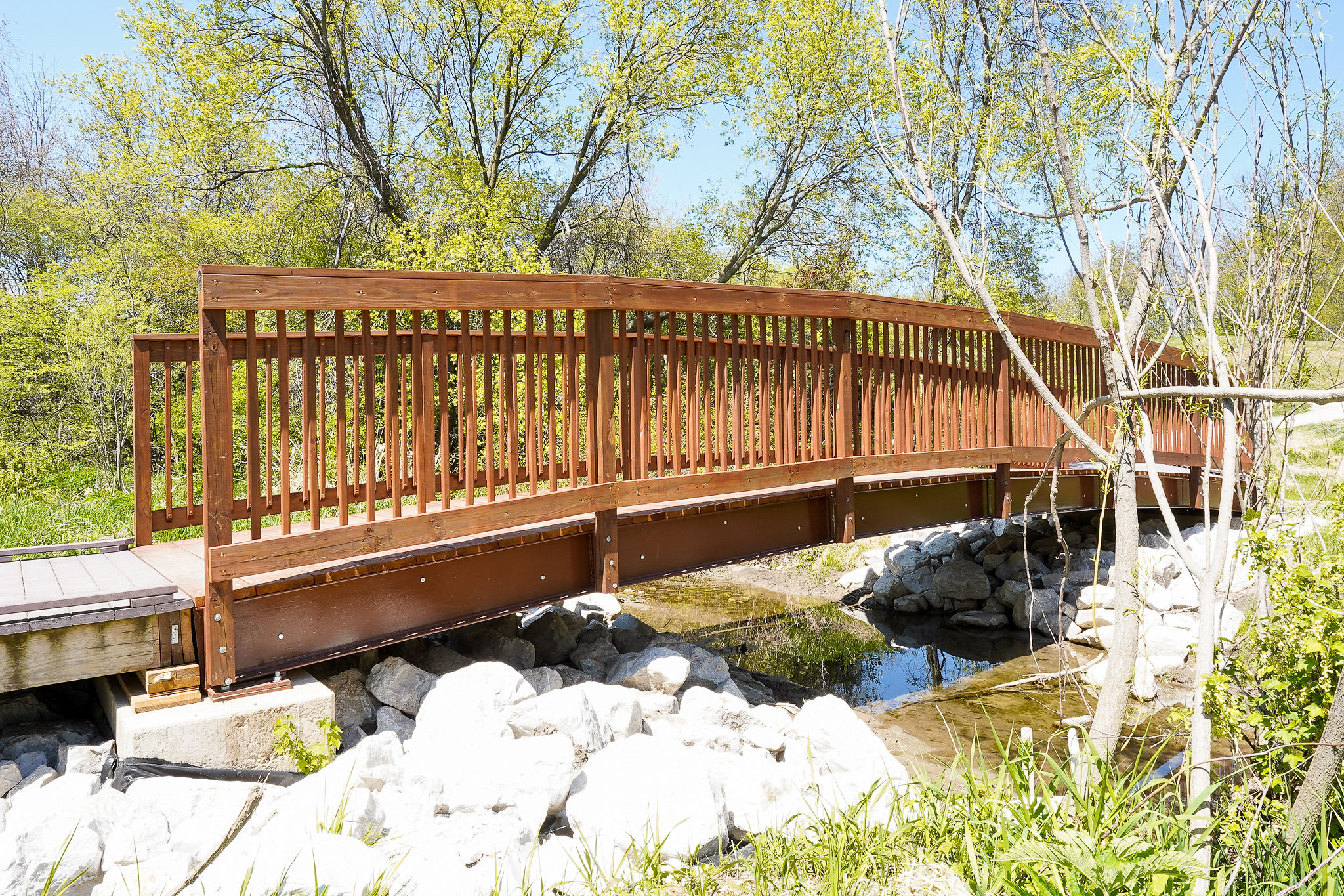 a wooden bridge over a stream with rocks