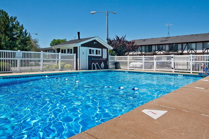 a swimming pool with a house and a white fence around it