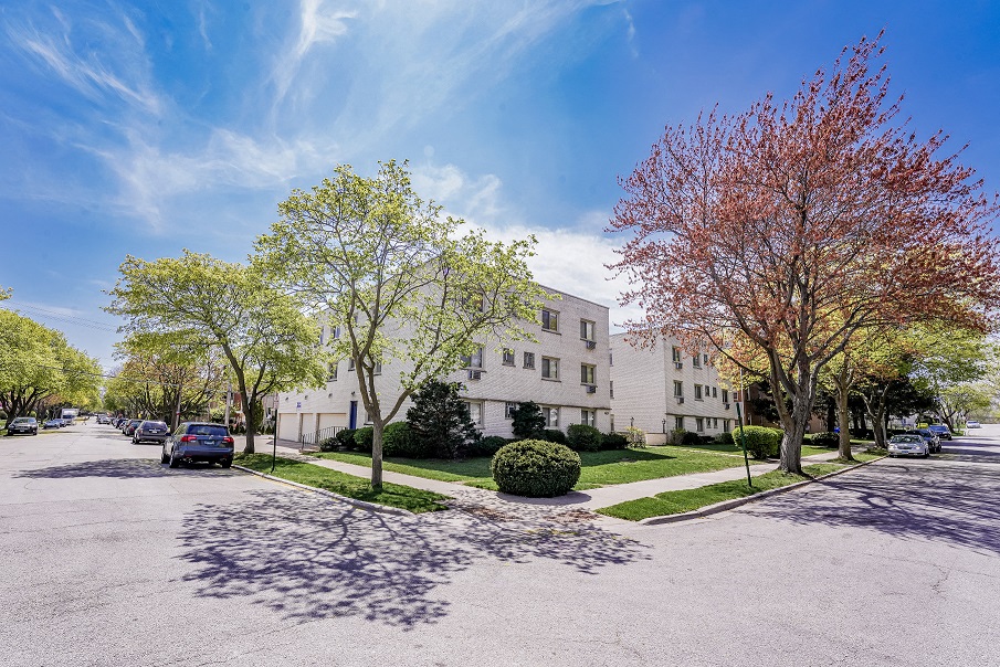 the view of an apartment building from the corner of a street