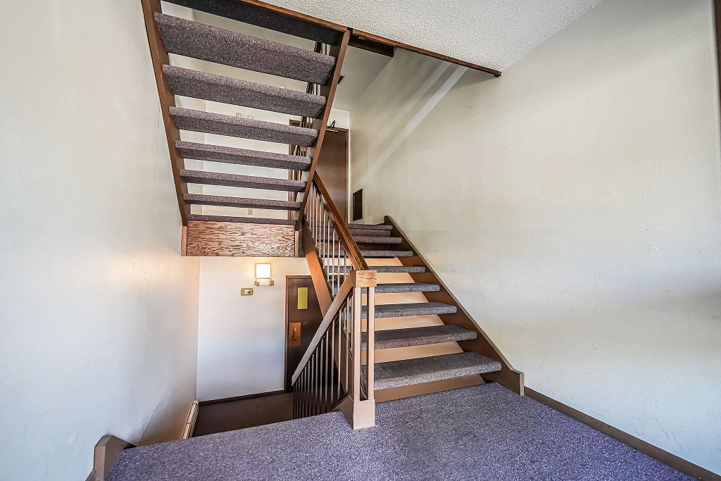 a staircase in a house with a wooden railing and carpeted stairs