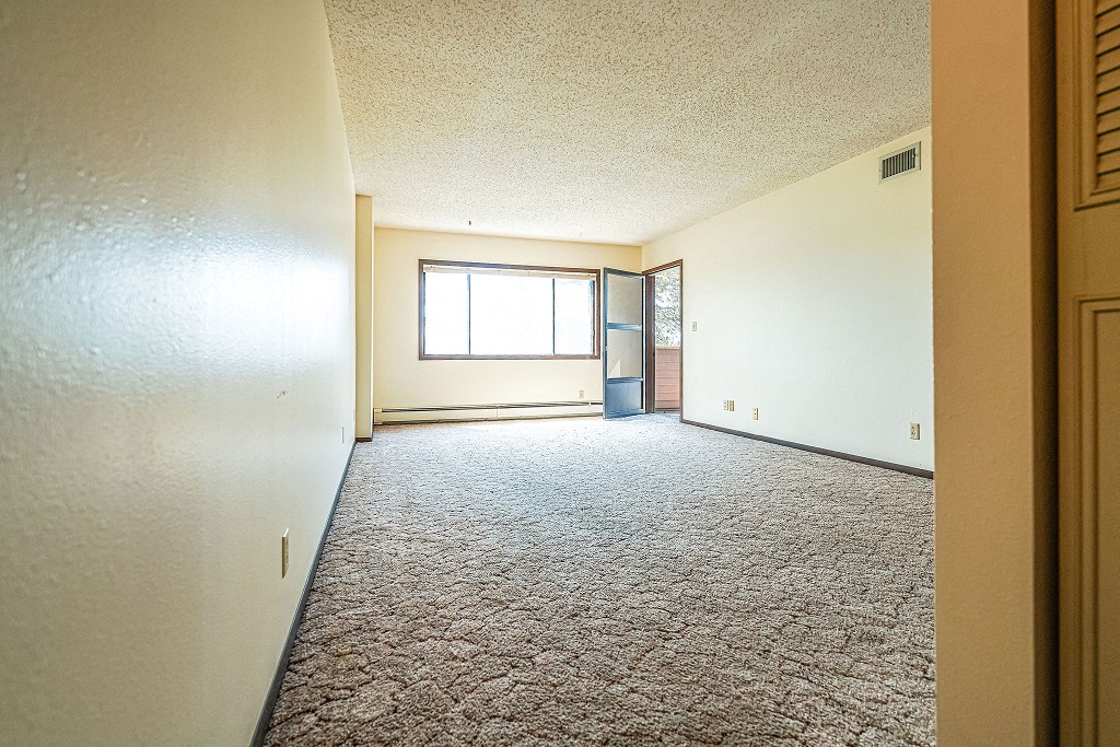 an empty living room with a window and a door