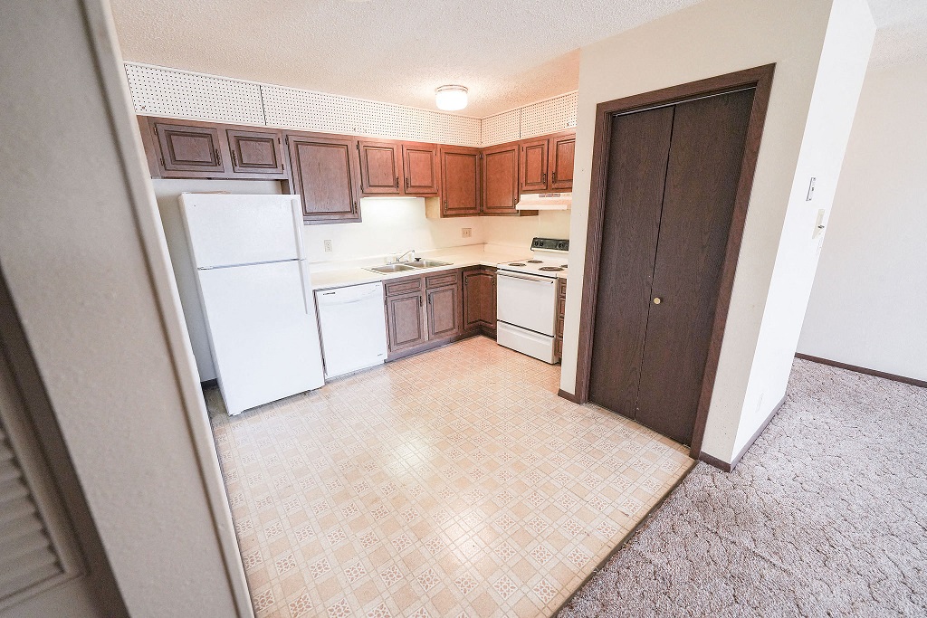 an empty kitchen with white appliances and wooden cabinets