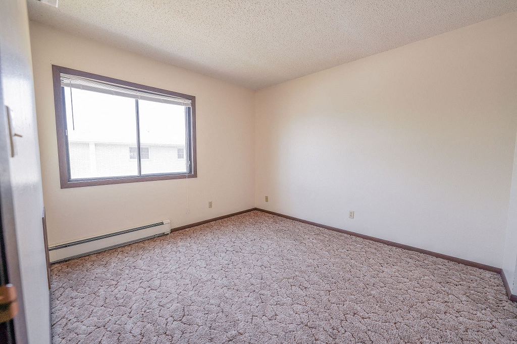 a bedroom with a large window and a carpeted floor