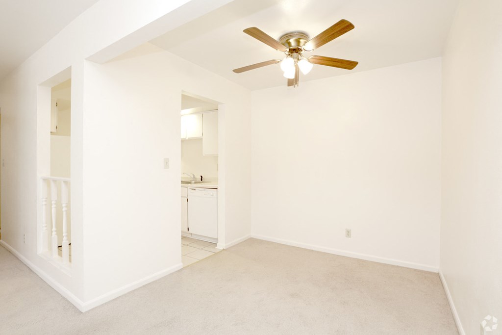 an empty living room with a ceiling fan