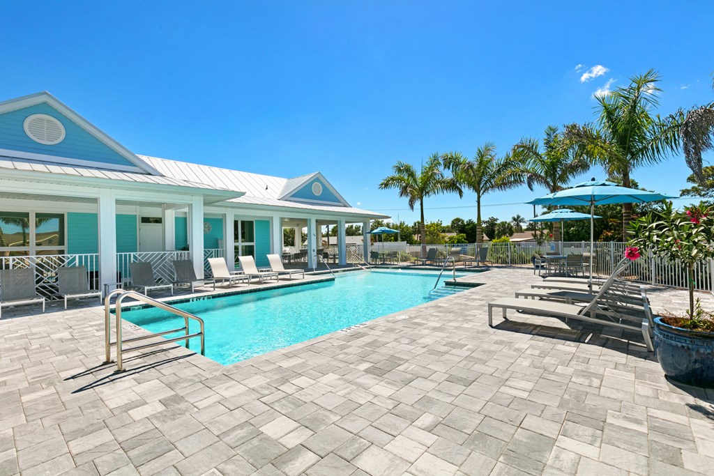 the swimming pool at the resort style pool house with chairs and umbrellas