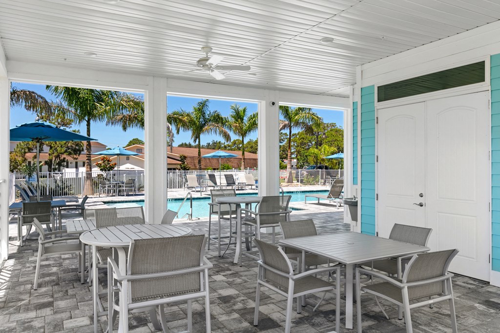 a covered patio with tables and chairs and a swimming pool
