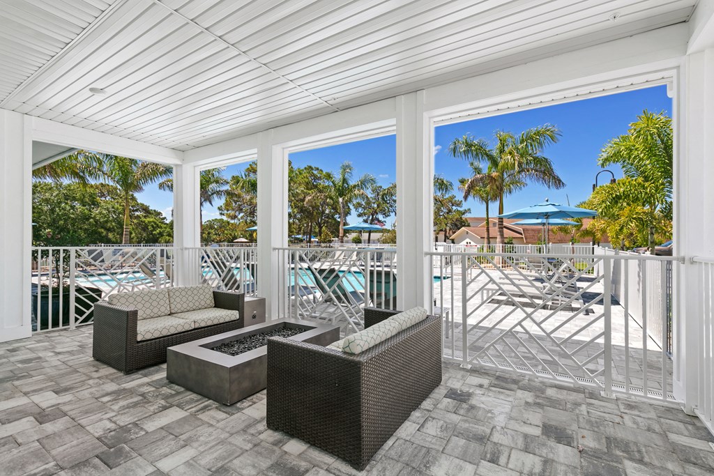 a covered patio with couches and chairs and a pool