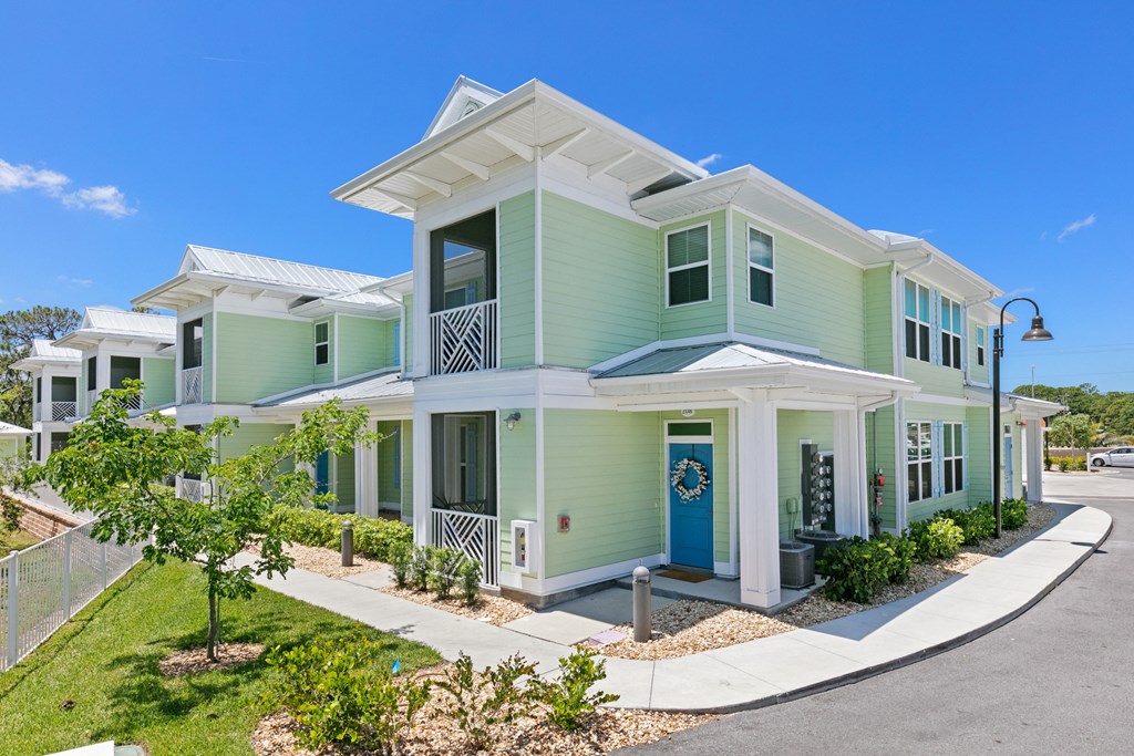 a green house with a sidewalk in front of it
