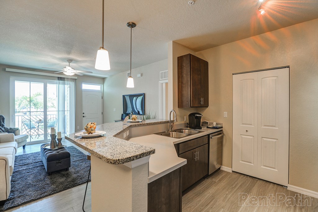 an open kitchen and living room with a door to a balcony