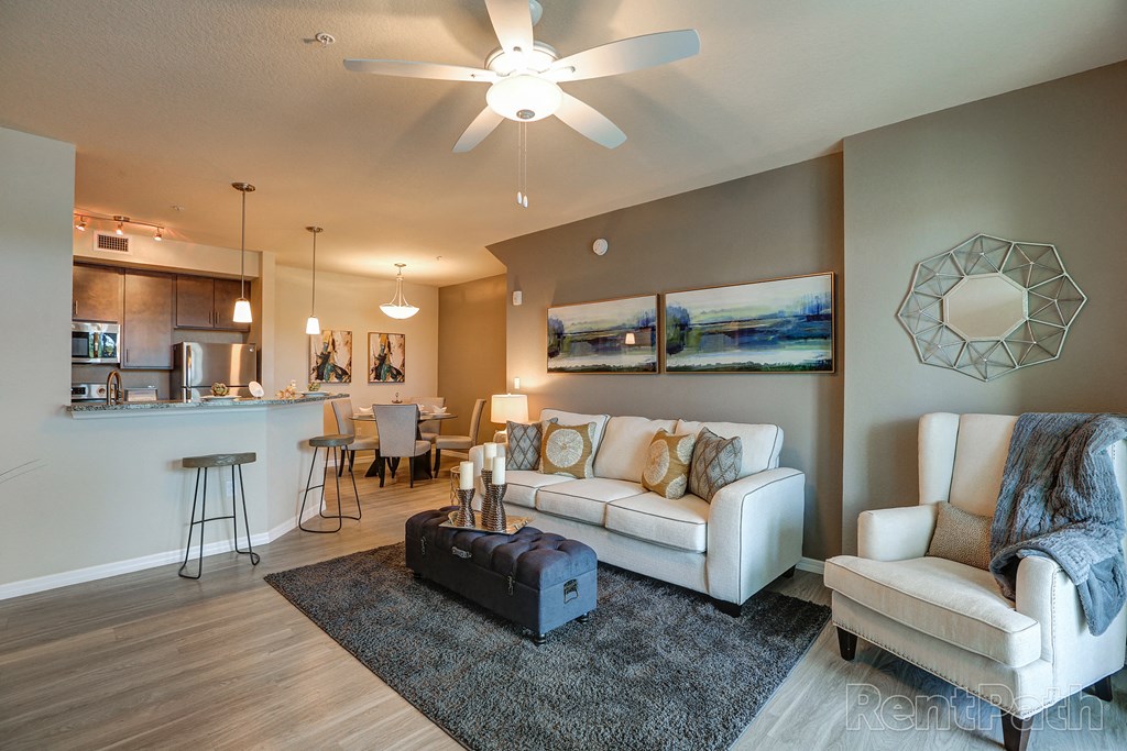 a living room and kitchen with a ceiling fan and a couch