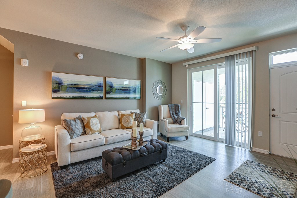 a living room with a couch and chairs and a ceiling fan