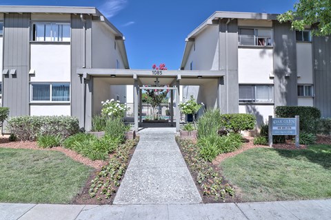 The image shows a pathway leading to a building with a sign