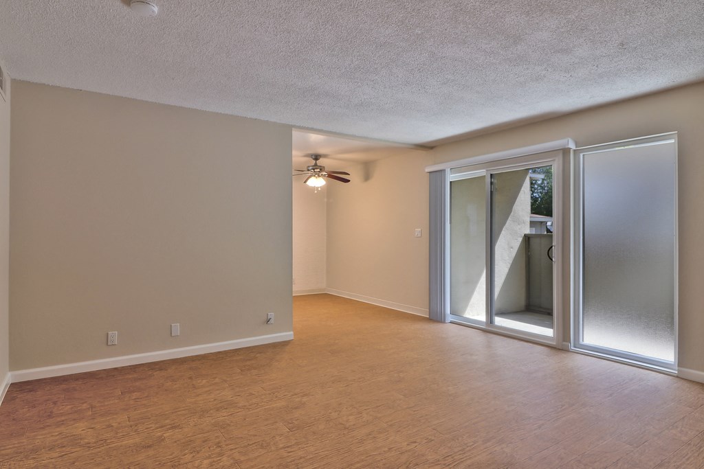 an empty living room with sliding glass doors and a ceiling fan