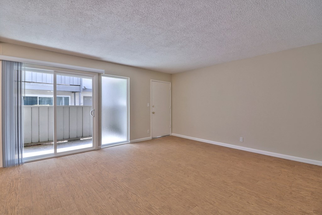 an empty living room with sliding glass doors to a balcony