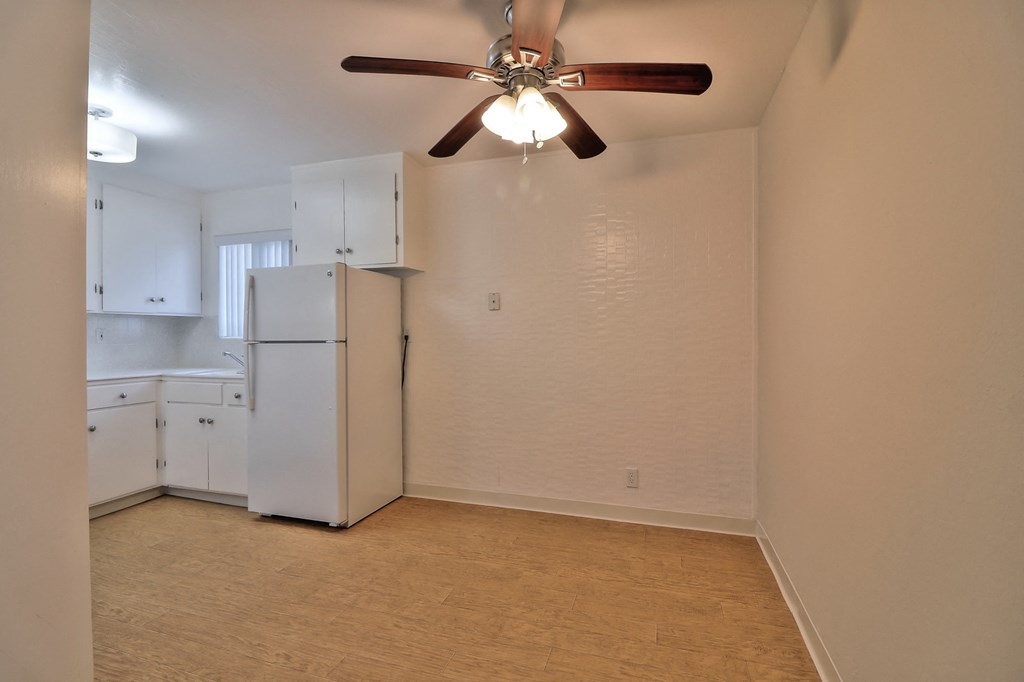 an empty kitchen with a ceiling fan and a refrigerator