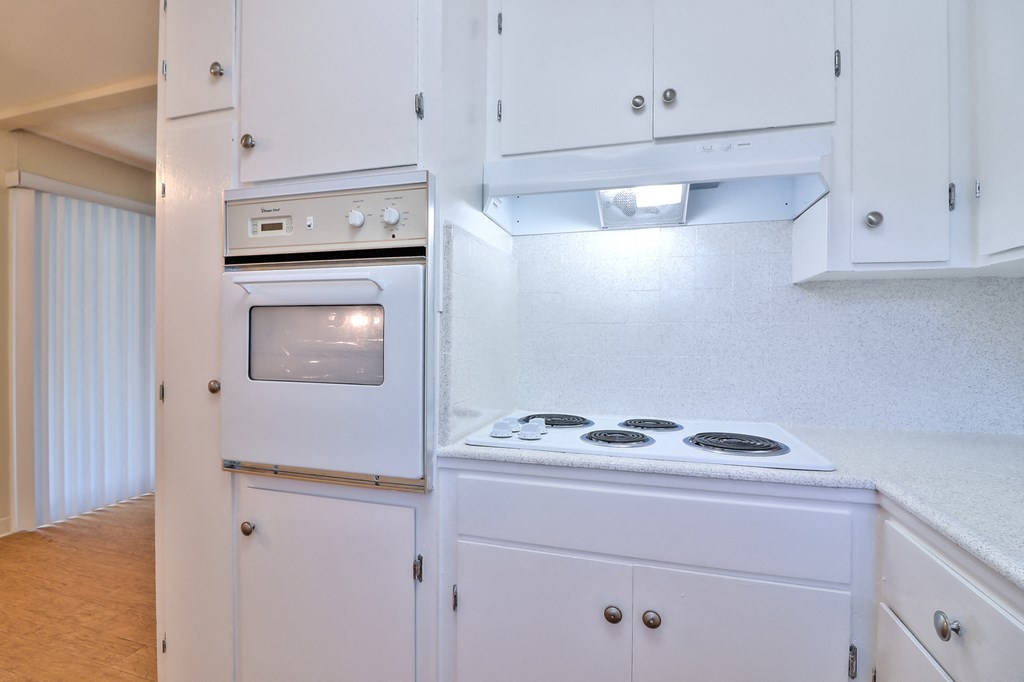 a kitchen with white cabinets and a stove and oven