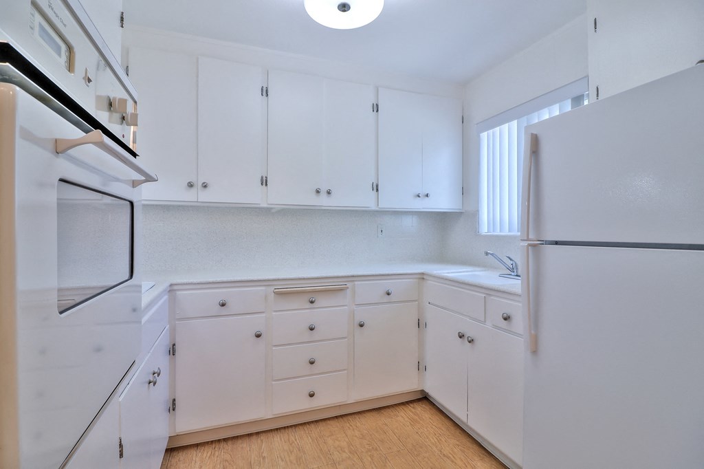 an empty kitchen with white cabinets and a refrigerator