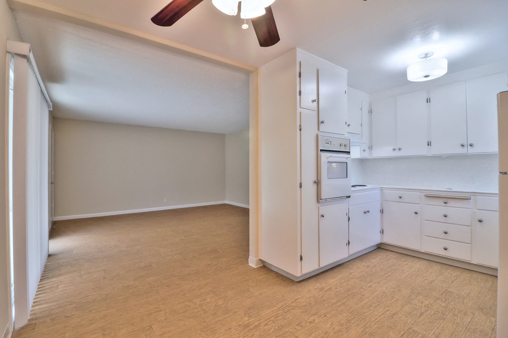 an empty kitchen with white appliances and white cabinets