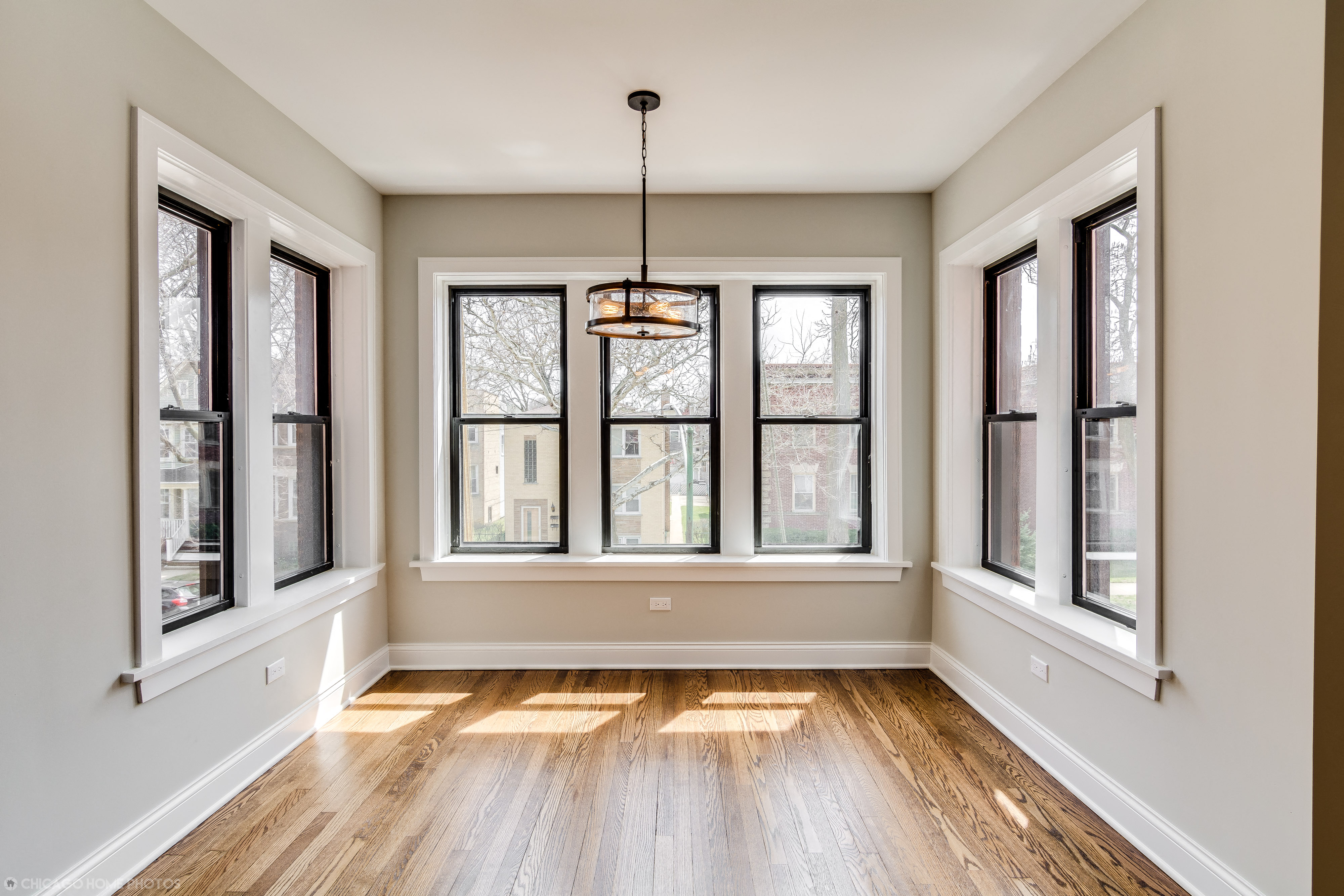 an empty living room with windows and wood floors